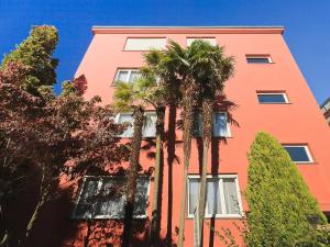 ein rosafarbenes Gebäude mit Palmen davor in der Unterkunft Apartment Junior Suite-8 by Interhome in Ascona