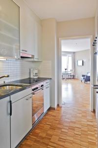 uma cozinha com armários brancos e piso em madeira em Apartment Double Room Modern-3 by Interhome em Ascona
