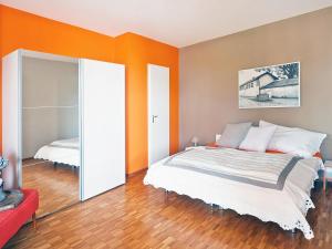 アスコナにあるApartment Junior Suite Modern-24 by Interhomeのオレンジ色の壁のベッドルーム1室(ベッド1台、鏡付)