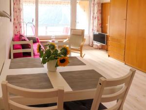 uma sala de estar com uma mesa com um vaso de flores em Apartment Promenade - Utoring-71 by Interhome em Arosa