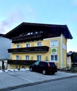 un furgone nero parcheggiato di fronte a un edificio giallo di Frühstückspension Klein und Fein a Bad Hofgastein