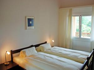 a bedroom with a bed with two lamps and a window at Apartment Residenza Parcolago Apt 203 by Interhome in Caslano