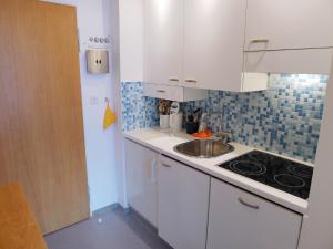 małą kuchnię z białymi szafkami i zlewem w obiekcie Apartment Promenade - Utoring-68 by Interhome w mieście Arosa