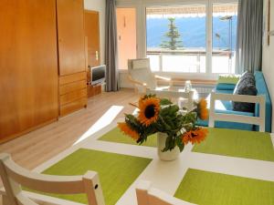 una sala de estar con una mesa con girasoles. en Apartment Promenade - Utoring-72 by Interhome en Arosa