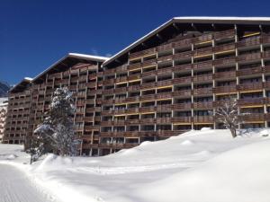 Un gran edificio con nieve delante. en Apartment Apt C 015 by Interhome, en Disentis
