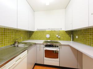 eine Küche mit weißen Schränken und grünen Fliesen in der Unterkunft Apartment Guardaval - Utoring-22 by Interhome in Davos