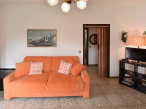 ein orangefarbenes Sofa im Wohnzimmer mit einem TV in der Unterkunft Holiday Home Villa Laura by Interhome in Vesta
