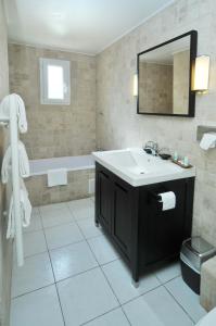 La salle de bains est pourvue d'un lavabo et d'une baignoire. dans l'établissement Hôtel Pineto, à Biguglia