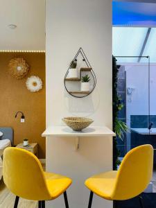 two yellow chairs and a shelf with plants on it at NG SuiteHome - Lille I Roubaix I Gare I Métro Alsace - Grand T2 - Balnéo - Netflix - Wifi - Cuisine in Roubaix