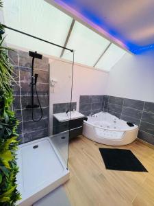 La salle de bains est pourvue d'une douche en verre et d'une baignoire. dans l'établissement NG SuiteHome - Lille I Roubaix I Gare I Métro Alsace - Grand T2 - Balnéo - Netflix - Wifi - Cuisine, à Roubaix