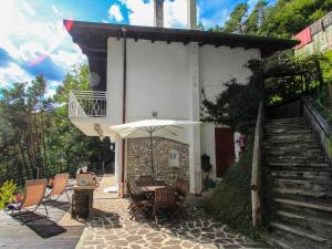 eine Terrasse mit einem Tisch, Stühlen und einem Sonnenschirm in der Unterkunft Holiday Home Rosemarie by Interhome in Mezzolago