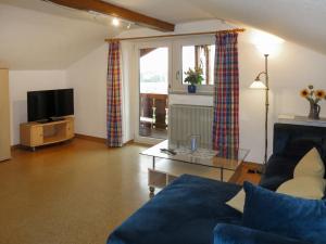 a living room with a blue couch and a tv at Apartment Fischer by Interhome in Lechbruck