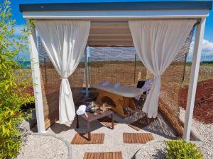 a patio with white curtains and a table at Holiday Home Camping Kastanija-1 by Interhome in Novigrad Istria