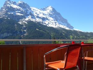 une chaise sur un balcon avec une montagne enneigée dans l'établissement Apartment Chalet Almisgässli by Interhome, à Grindelwald