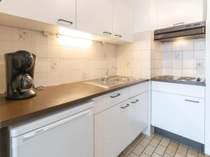 a kitchen with white cabinets and a sink at Apartment Residentie Astrid-1 by Interhome in Bredene