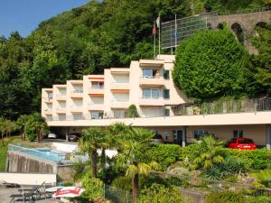 ein Hotelgebäude mit einem Pool und Palmen in der Unterkunft Apartment Aldesago Monte Brè - Utoring-7 by Interhome in Viganello
