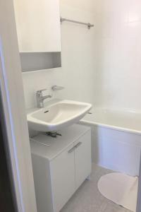 a white bathroom with a sink and a tub at Apartment Val Signina-2 by Interhome in Laax-Murschetg