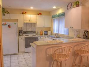 a kitchen with white appliances and two bar stools at Holiday Home Sunrise by Interhome in Palm Coast