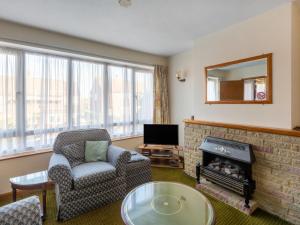 a living room with a fireplace and a chair and a tv at Holiday Home Trappers End by Interhome in Whitstable