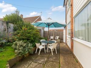 a patio with a table and chairs and an umbrella at Holiday Home Trappers End by Interhome in Whitstable