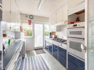 a kitchen with white cabinets and blue counters at Holiday Home Jeanettes by Interhome in New Malden