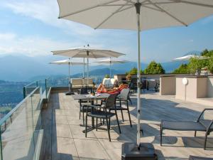 een patio met tafels, stoelen en parasols bij Apartment Aldesago Monte Brè - Utoring-28 by Interhome in Viganello