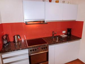 a kitchen with white cabinets and a sink and a stove at Apartment Residenza Monte Bré - Apt-004 Haus1 by Interhome in Lugano