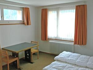 Cette chambre comprend une table, un lit, une table et une fenêtre. dans l'établissement Apartment Parkareal - Utoring-49 by Interhome, à Davos