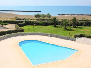 an empty swimming pool in front of a beach at Apartment Les Rivages de Rochelongue-4 by Interhome in Cap d'Agde