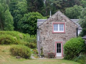 a stone house with a red window and a yard at Holiday Home Lorn Mill-2 by Interhome in Balloch