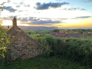 a stone wall with a sunset in the background at Holiday Home Moonfleat Cottage by Interhome in West Quantoxhead