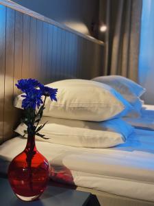 a white vase with flowers sitting on a bed at LA Hotel in Lidingö