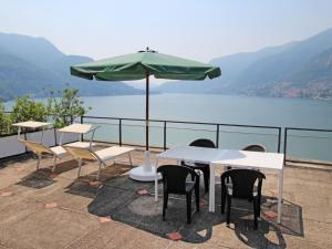 a table and chairs with an umbrella and a lake at Apartment La Cava-8 by Interhome in Pognana Lario