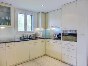 a white kitchen with white cabinets and a window at Holiday Home Chalet Aaregg by Interhome in Brienz +28 photos