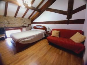 1 dormitorio con 1 cama y 1 sofá rojo en Errotazar apartamento rural P, en Alsasua
