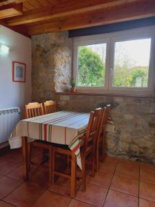 a dining room with a table and chairs and two windows at Errotazar apartamento rural P in Alsasua