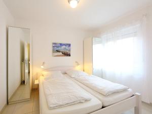 ノルトダイヒにあるApartment Jolle by Interhomeの白いベッドルーム(ベッド1台、鏡付)