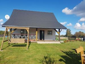 a small house with a black roof on a yard at Holiday Home Modrzewiowy Zakątek by Interhome in Smołdziński Las