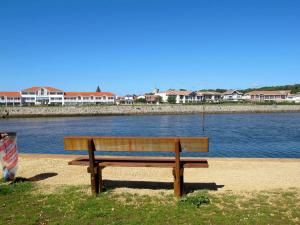 a wooden bench sitting next to a body of water at Holiday Home Le Hameau des Pêcheurs 5-1 by Interhome in Mimizan-Plage