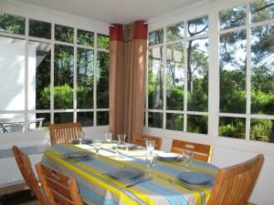 a dining room with a table with chairs and windows at Holiday Home Les Bruyères by Interhome in Mimizan-Plage