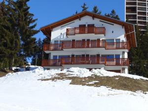 a house with a balcony on top of snow at Apartment Les Aiguilles Vertes Rez inférieur by Interhome in Crans-Montana