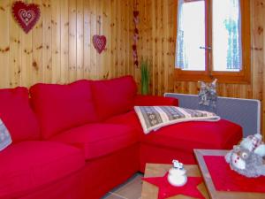 a living room with a red couch and a table at Chalet Le Ruisseau by Interhome in Nendaz