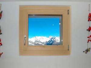 a window with a view of a snow covered mountain at Chalet Le Ruisseau by Interhome in Nendaz