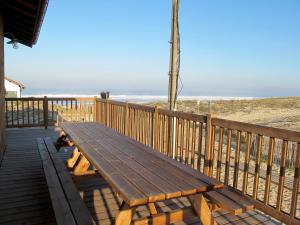 un banco de madera sentado en una terraza cerca de la playa en Holiday Home Les Mouettes by Interhome, en Mimizan-Plage