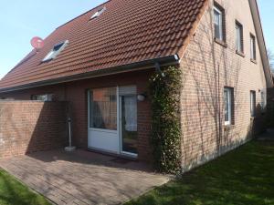 a brick house with a white door and ivy at Holiday Home Robbe by Interhome in Norddeich