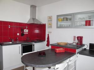 ミミザン・プラージュにあるStudio Horizon-1 by Interhomeの赤と白の壁のキッチン(テーブル付)