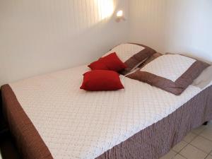 a bed with two red pillows on top of it at Studio Horizon-1 by Interhome in Mimizan-Plage