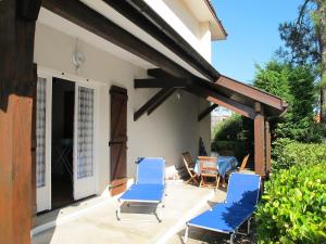 a patio with two blue chairs and a table at Holiday Home Tourterelles by Interhome in Mimizan-Plage