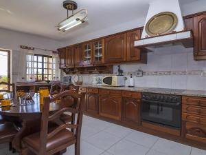 a kitchen with wooden cabinets and a table with chairs at Villa Villa Quinta do Sol by Interhome in Armação de Pêra