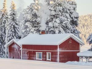 een rode schuur bedekt met sneeuw voor met sneeuw bedekte bomen bij Holiday Home Villa unari by Interhome in Unari